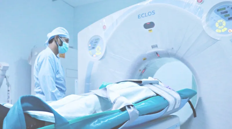 a man in a medical uniform and mask next to a patient lying on a ct scan machine